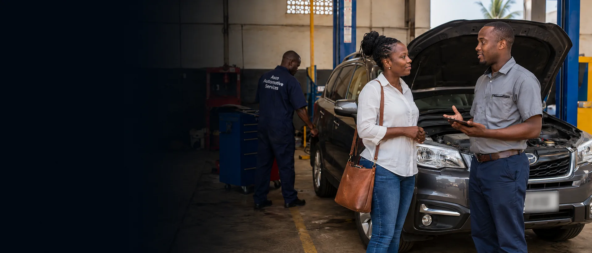 Asco Automotive Services adviser speaking with a customer beside a vehicle in the workshop